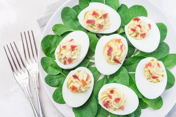 Avokado, yumurta sarısı ve mayonez ile doldurulmuş yumurtalar, pastırmayla süslenmiş, ıspanak yapraklarıyla süslenmiş, yatay, üst manzara