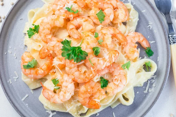 Pasta with shrimps in creamy parmesan cheese and garlic sauce garnished with parsley, fettucini alfredo, horizontal, top view,  closeup