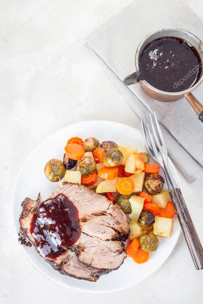 Pork shoulder in honey parmesan and soy souse, prepared in slow cooker or crockpot, served with carrot, potato and brussel cabbage, on a white plate, vertical, top view, copy space