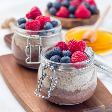 Kavanozda çikolata ve fıstık ezmeli chia tohumu pudingi, ahududu ve yaban mersiniyle süslenmiş, kare