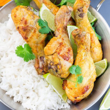 Hint tavuk tandırı, Yunan yoğurdu ve baharatlarıyla marine edilmiş, limon dilimleri, kişniş ve basmati pilavı ile servis ediliyor, üst manzara, kare format