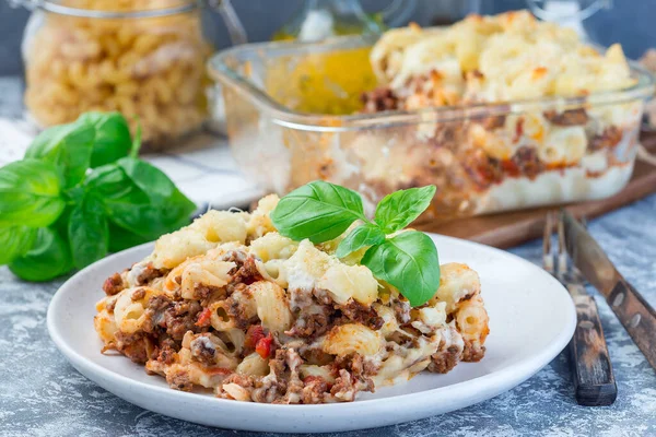 Macaroni casserole with ground beef, cheese and tomato on a plate, horizontal