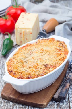 Baharatlı domates biberli makarna ve peynirli mini makarna, fırın kabında, dikey.