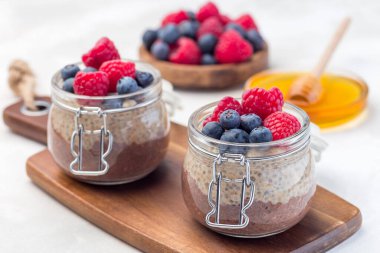 Kavanozda çikolata ve fıstık ezmeli chia tohumu pudingi, ahududu ve yaban mersiniyle süslenmiş, yatay