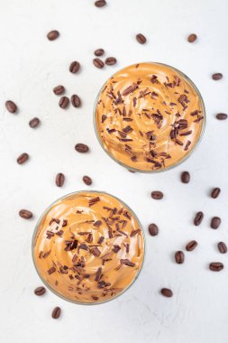 Buzlu Dalgona kahvesi, rendelenmiş çikolata, kavanozda hazır kahve, açık gri arka plan, dikey, üst manzara, yakın çekim.