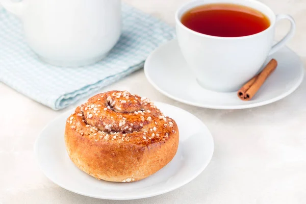 白盘上的一个肉桂面包 配上一杯红茶 水平的 — 图库照片