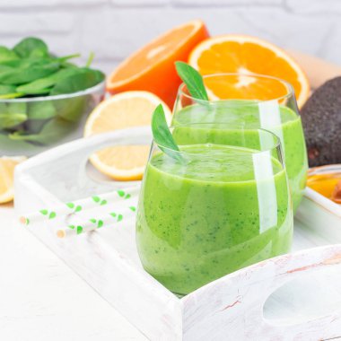 Yeşil detoks smoothie ile avokado, ıspanak, salatalık, portakal, limon ve bal, ahşap tepside, kare