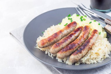 Kızarmış nuremberg sosisleri ekşi lahana ve patates püresiyle servis edilir gri bir tabakta, yatay, kopyalama alanı