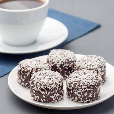 İsveç çikolatalı topları ya da çikolatalı bollar, yulaf, kakao, hindistan cevizi, tereyağı ve tereyağı, beyaz bir tabakta, kahveyle servis edilir, kare formatta.