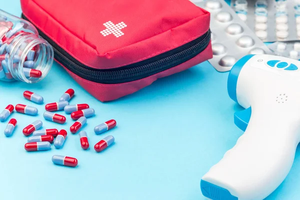 Different medicine on the table, first aid kit, thermometer and pills, on a blue background, horizontal, copy space