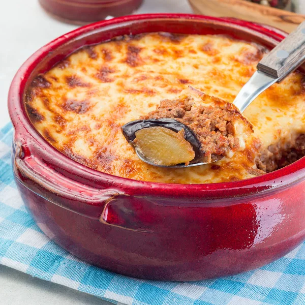 Greek dish moussaka made in a traditional ceramic pot, square format, closeup