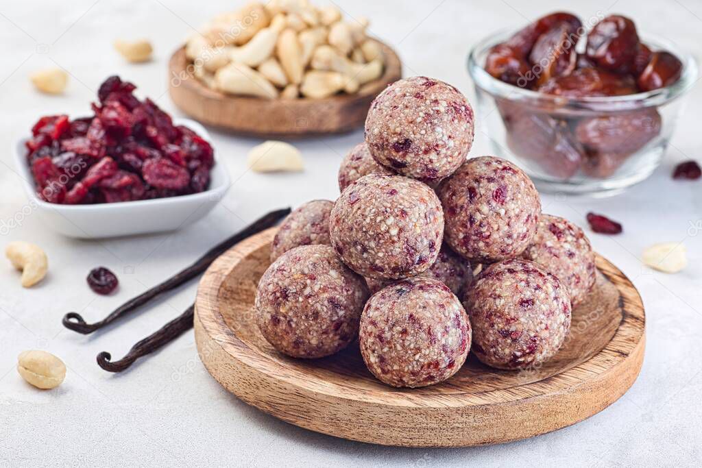 Healthy homemade energy balls with cranberries, cashew nuts, dates and vanilla on a wooden plate,  horizontal