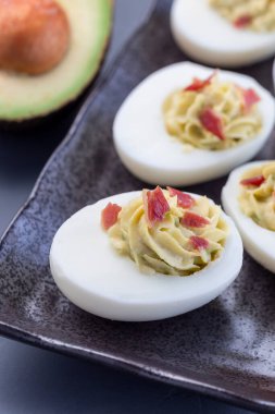 Avokado, yumurta sarısı ve mayonez ile doldurulmuş, pastırmayla süslenmiş, dikey...