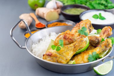 Yunan yoğurt ve baharatlarıyla marine edilmiş Hint tavuğu tandır. Limon dilimleri, kişniş ve basmati pilavı ile servis edilir.