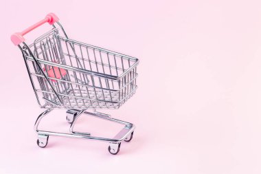 Pembe arka planda küçük boş alışveriş arabası, kopyalama alanı, yatay