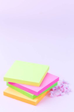 Boş renkli notlar yığını, yanında iğneler, pembe arkaplandaki kırtasiye, dikey, kopyalama alanı