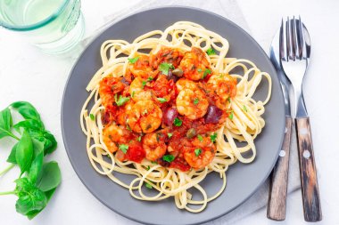 Baharatlı domates fesleğen soslu makarna maydanozla süslenmiş gri bir tabakta, yatay ve üst manzaralı.