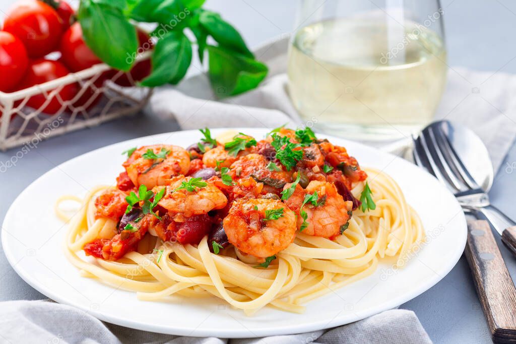 Italian dish shrimp linguine Puttanesca, pasta with shrimps in spicy tomato basil sauce garnished with parsley,  horizontal