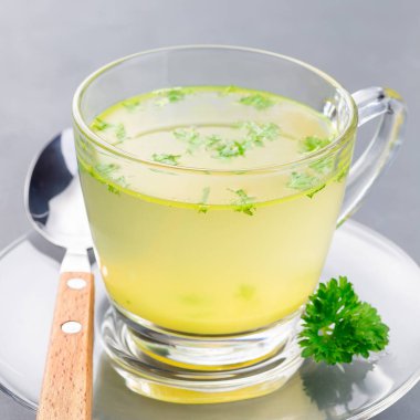 Cam bardakta tavuk suyu ve doğranmış maydanoz. Kare şeklinde.