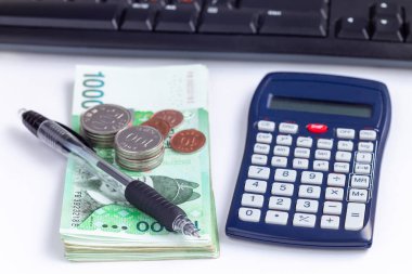 Bir hesap makinesi, kalem ve klavye yanında 10 bin won değerinde Güney Kore para yığını, para tasarrufu kavramı