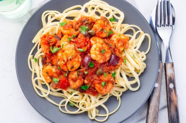 Karides linguine Puttanesca makarnası baharatlı fesleğen soslu karides, gri tabakta, üst manzara, yatay