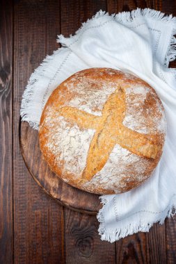 Yavaş mayalanma yok klasik Boule ekmeği, tahta bir tahtanın üzerinde yuvarlak bir somun, beyaz bir bez, dikey, üst görünüm 