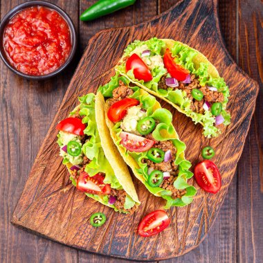 Etli taco, avokado püresi, domates, marul, kırmızı soğan, jalapeno biberi, kare, üst manzara.