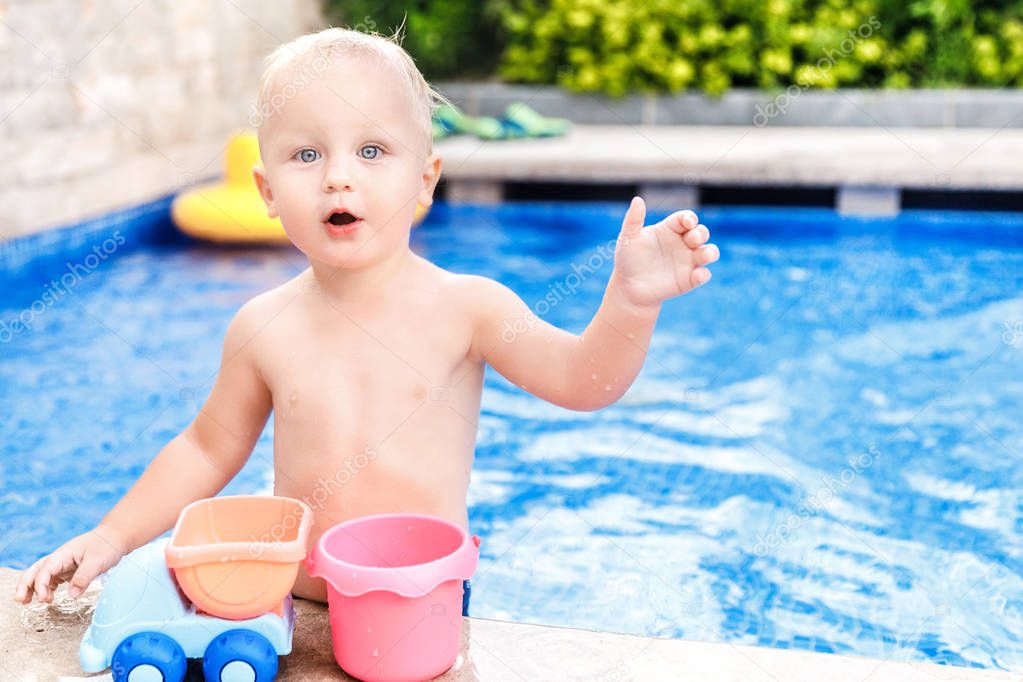 Little toddler in water pool in the summer day