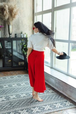 muhteşem esmer kadın arround dans açın. geniş bacaklı ve beyaz gömlekli kırmızı moda tavakadın. ayakkabı olmadan kanepede siyah saçlı moda genç kadın kapalı. rahat ev konsepti. Iyi