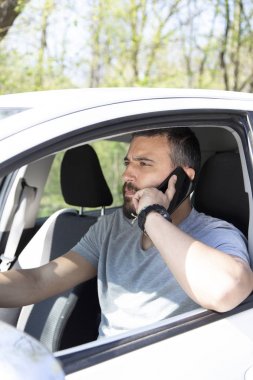 Adam araba kullanırken cep telefonuna bakıyor..