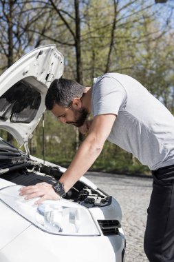 Yoldaki arızalı arabanın önündeki genç adam.