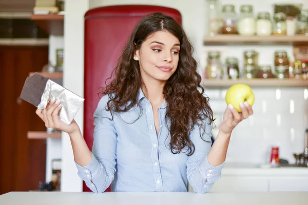 Confused woman on diet, what to eat, chocolate or apple