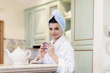 Genç ve güzel bir kadın sabahları mutfakta çay içiyor.