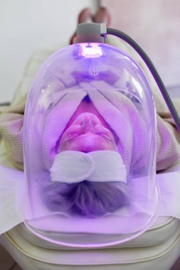 Yüz için renk ışığı terapisi alan kadın. Yüz terapisi. Anti-aging prosedürleri.