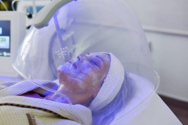 Yüz için renk ışığı terapisi alan kadın. Yüz terapisi. Anti-aging prosedürleri.