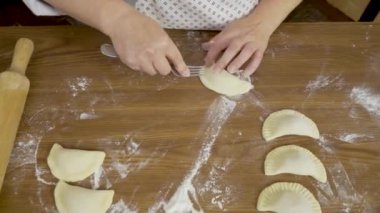 Video klipte İtalyan usulü raviyolis pişiriyor. Şef Asya usulü köfte, buğday ununu yakın çekim görüntüsünde pişiriyor. Aşçı, mutfak masasında ahşap leğen otu hazırlıyor.