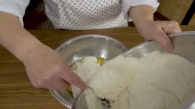Kapat - eller evdeki masada hamuru yoğur. Elleri mutfakta hamuru hazırlayan bir kadının yakın çekimi.