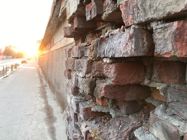 Gün batımında yol kenarındaki yıkılmış duvar.