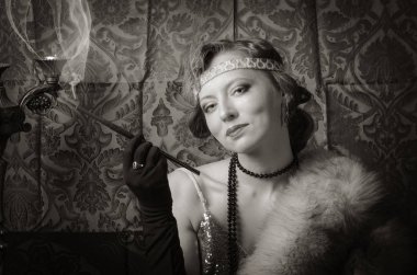 Bir sigara ağızlık ile bir gece elbisesi kız. Stüdyo portre retro tarzı, tonda sepya içinde