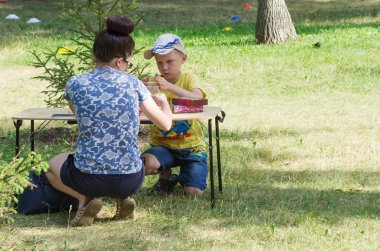 Genç bir anne ile oğlu genel bir parkta masa oyunları oynar. 06/29/2018: Rusya, Orenburg, Perovsky Park Resmin çekildiği. Aile tatilleri