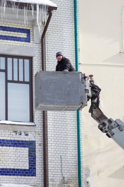 Bir gondol araba Asansör arka planda bina cephe işçi. Orenburg, Rusya - Şubat, 21, 2019: buz sarkıtları çatılar ve binaların saçak kaldırma aletleri yardımıyla temizlik