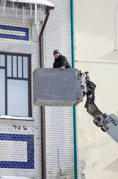 Bir gondol araba Asansör arka planda bina cephe işçi. Orenburg, Rusya - Şubat, 21, 2019: buz sarkıtları çatılar ve binaların saçak kaldırma aletleri yardımıyla temizlik