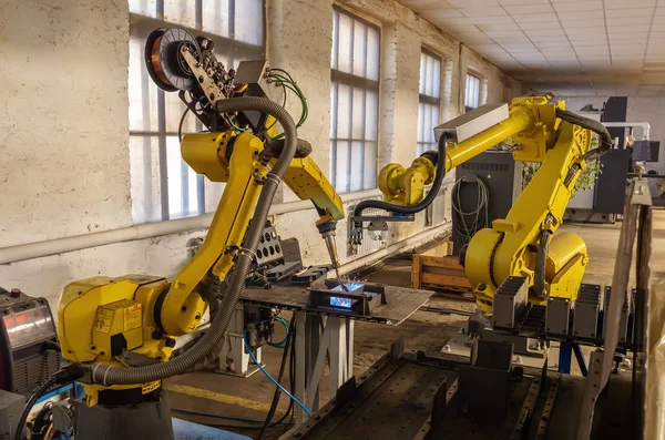 Robots in production. Work of the welding robot and manipulator robot on the factory floor