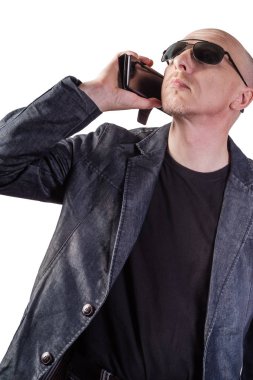 Kot ceketli, güneş gözlüğü takan, cep telefonuyla konuşan bir adam. Avrupa'ya ait orta yaşlı bir adam. Beyaz arka planda yalıtılmış