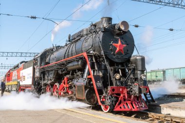 İstasyon platformunda buharlı lokomotif Serisi L. Orenburg, Rusya - 8 Mayıs 2019: Festival retro treninin Orenburg istasyonundan ayrılması