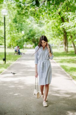 Şehir parkında yürüyüş yapan Asyalı bir kız. Yeşil yapraklı genç Tatar 'ın yaz portresi