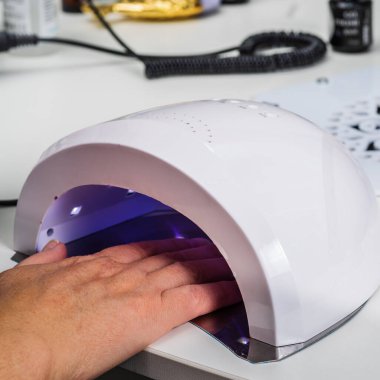 Nail salon, client's hand in a drying lamp, close-up