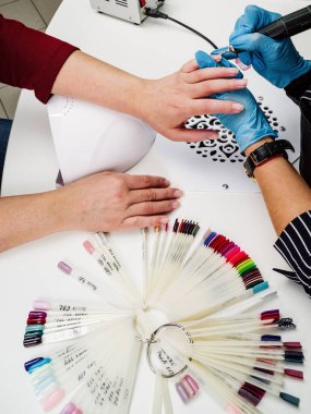 Nail salon, hands of client and master close-up. Nail treatment with a cutter