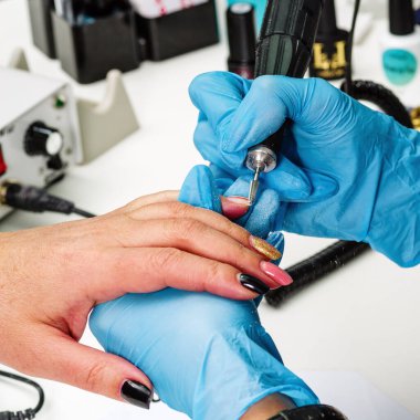 Nail salon, hands of client and master close-up. Nail treatment with a cutter