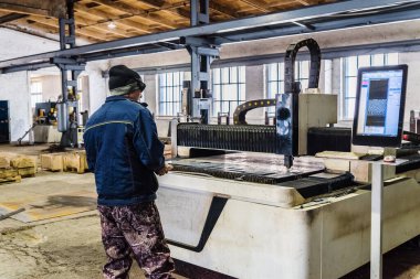 CNC lazer makinesinin operatörü. Fotoğraf fabrika katında çekildi.